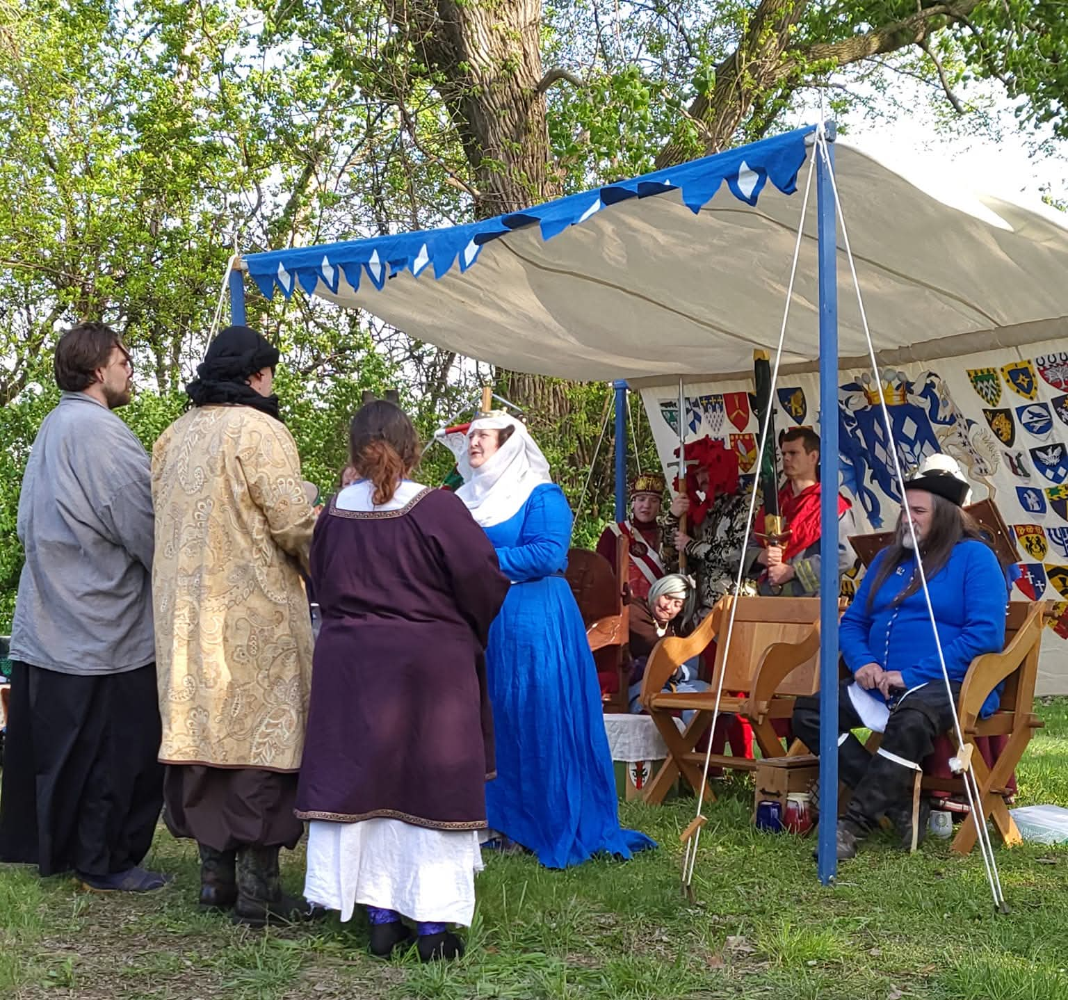 Members of the Society for Creative Anachronism greet their ruling monarchs. All are wearing historical costumes.