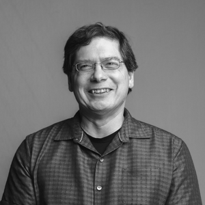 A black and white photograph of Dr. Scott Hamilton-Brehm, who is smiling and wearing glasses and a button-up shirt.